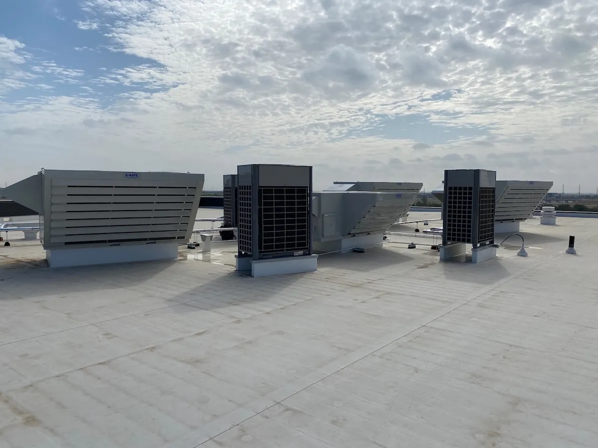 Row of packaged rooftop air handling units and VRF condensers on a commercial roof