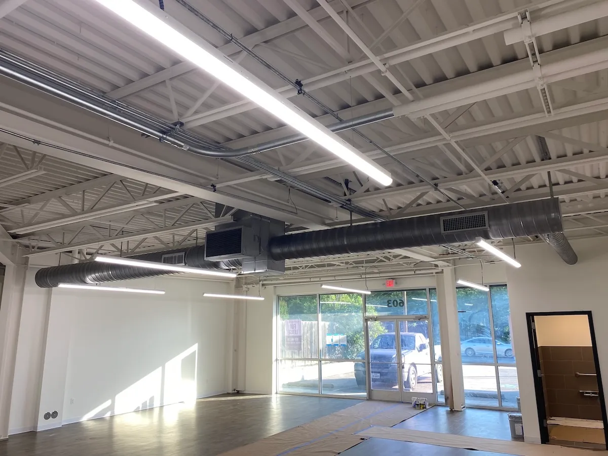 Exposed spiral ductwork and a suspended HVAC unit in a finished retail space