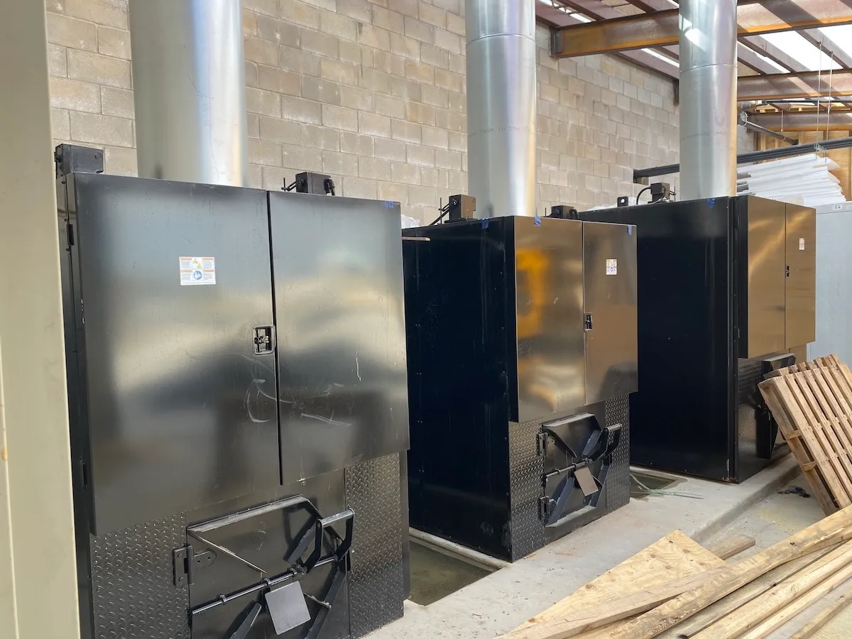 Black equipment cabinets with stainless flue stacks inside a warehouse