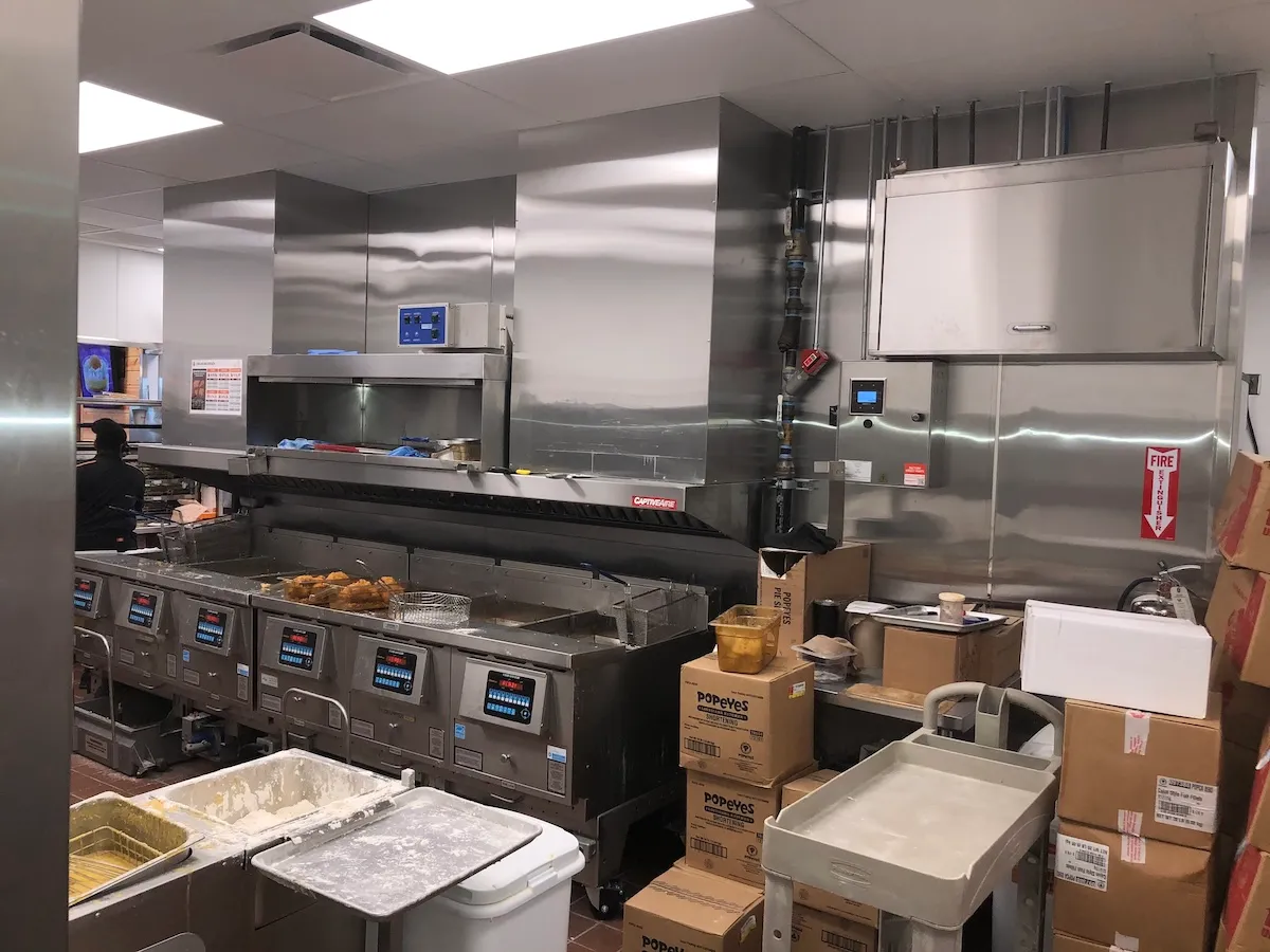 Commercial kitchen ventilation hood system in a quick-service restaurant kitchen